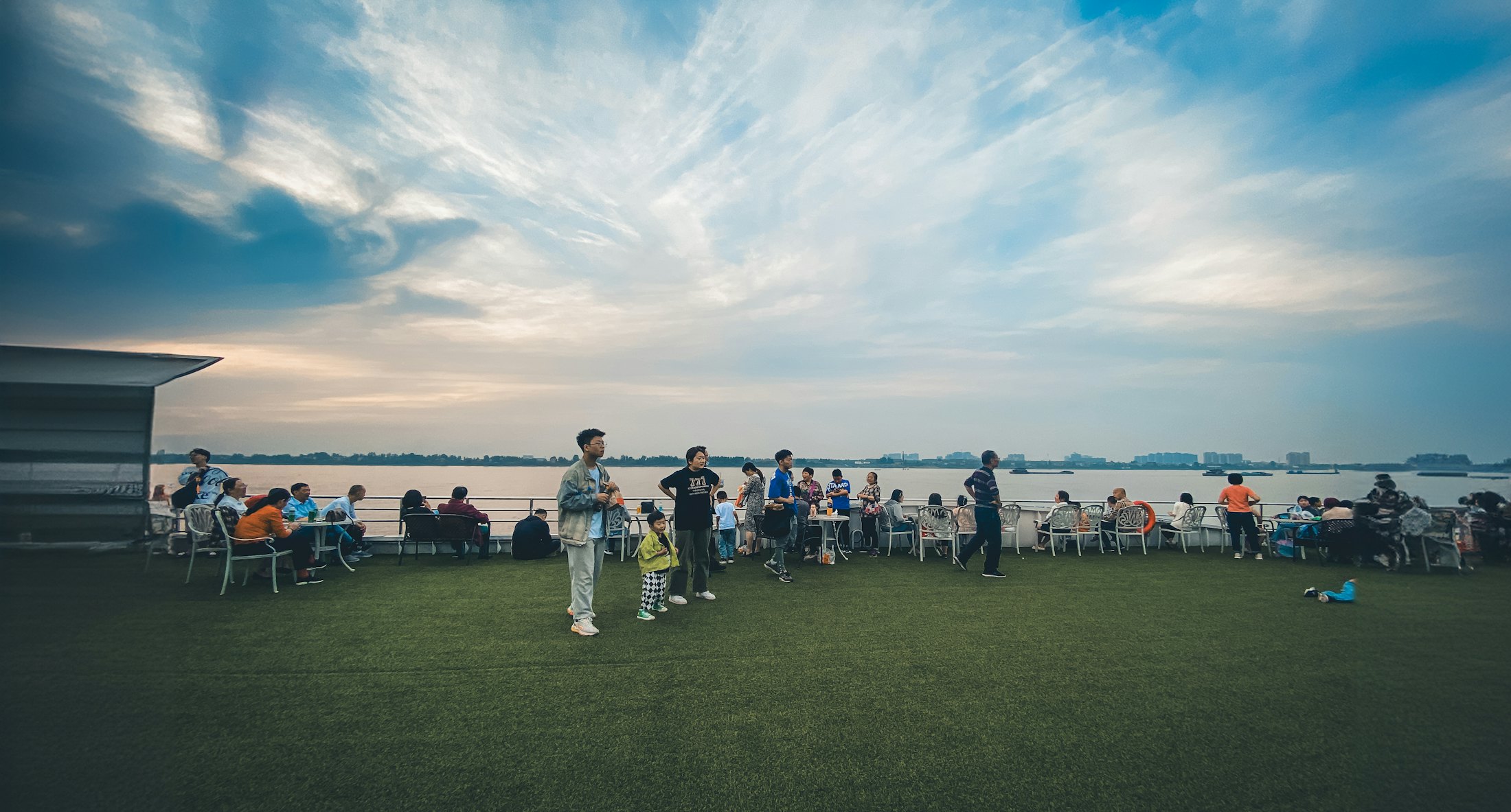 Club members gathered on a lawn beside the water in the evening.